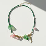 Green malachite and pink blossom beaded necklace with pearls on white background.