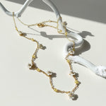 Delicate gold necklace with floral elements on a white surface