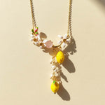 Necklace with lemon and flower pendants on a beige background