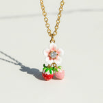 Necklace with a flower and strawberry pendant on a light background