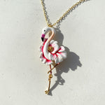 Flamingo-shaped pendant on a chain against a light background