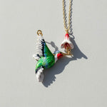 Colorful bird-shaped pendant on a chain with a flower-shaped end against a light gray background