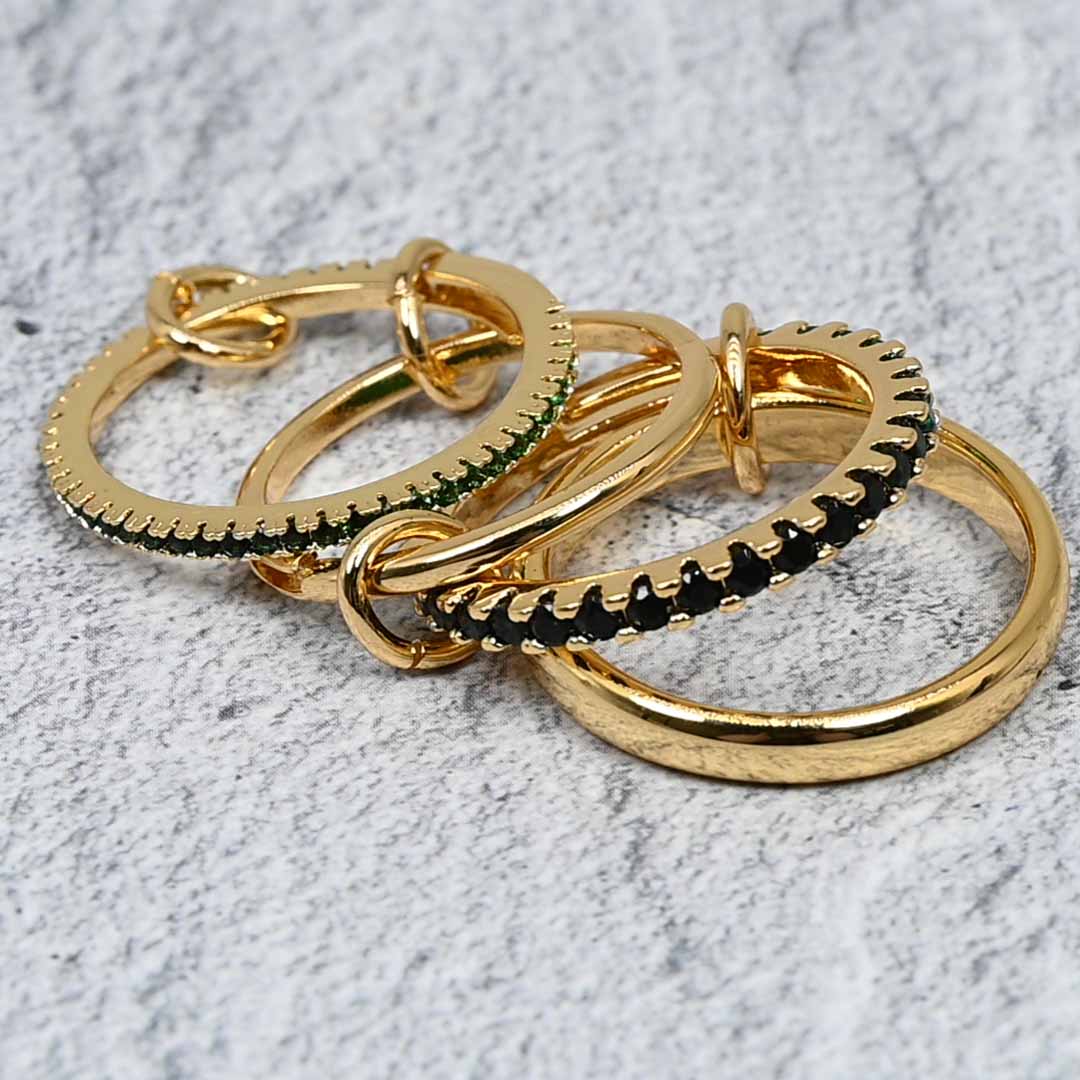 A set of four linked gold-plated rings featuring rich emerald-colored cubic zirconia stones. The rings have a polished and pavé finish, connected by delicate links for versatile styling and an adjustable fit.