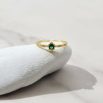 Gold ring with a green gemstone on a white stone surface