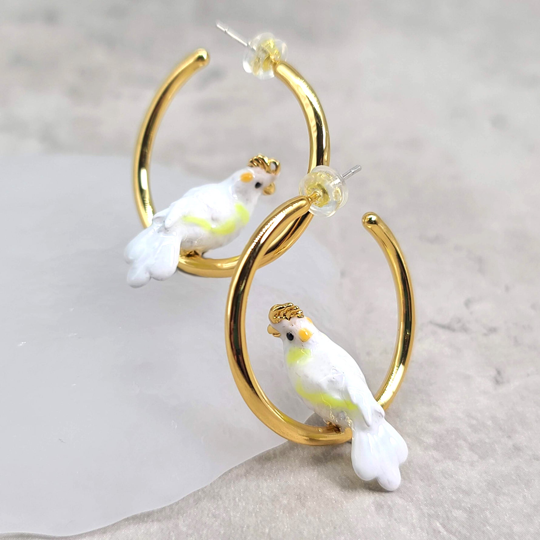 Gold-plated hoop earrings featuring charming white cockatoo bird details in enamel, perfect for adding playful elegance to your style
