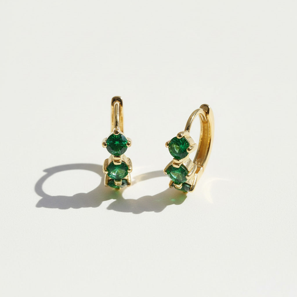 Gold-plated hoop earrings with three green birthstones in graduated sizes, elegant minimalist May birthstone design.
