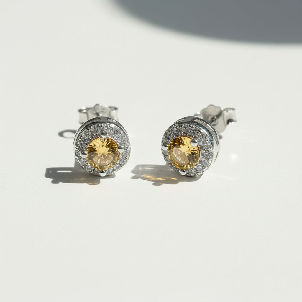 Silver stud earrings with platinum plating and yellow birthstone center, surrounded by sparkling CZ halo.