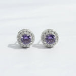 Silver stud earrings with platinum plating and purple birthstone center, surrounded by clear CZ halo.