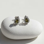 Teardrop silver stud earrings with platinum plating, green birthstone center, and halo of clear cubic zirconia.