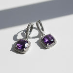 Amethyst birthstone dangle earrings with cushion-cut purple stones and halo CZ, platinum-plated silver leverback design.