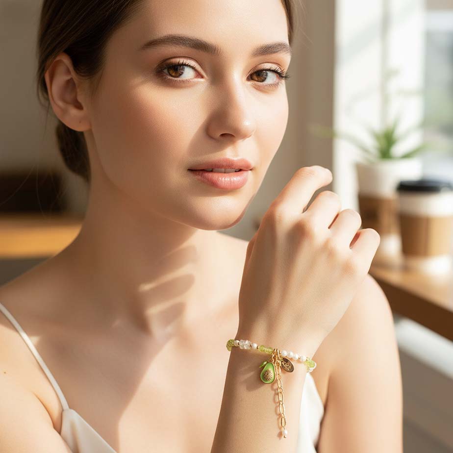Woman wearing a bracelet with a green charm in a softly lit room.