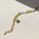 Bracelet with green stone and gold chain on a light fabric background