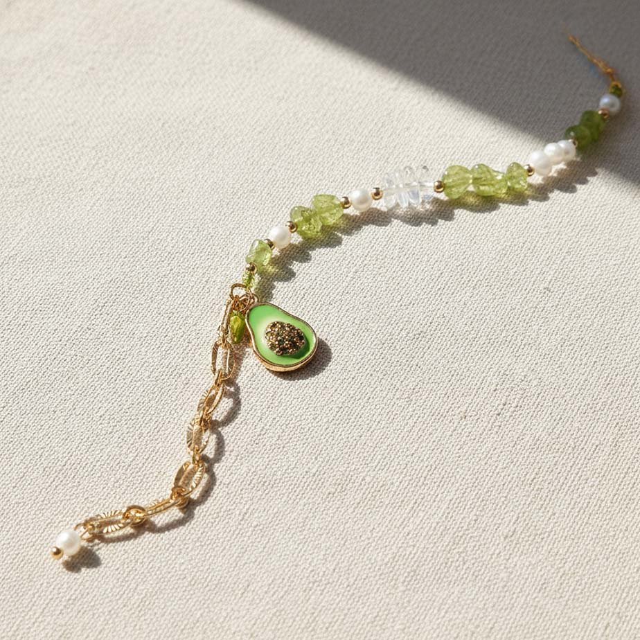 Bracelet with green stone and gold chain on a light fabric background
