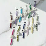Birthstone flower bracelets in 12 colours for each month, featuring white carved flower charms with gemstone beads.