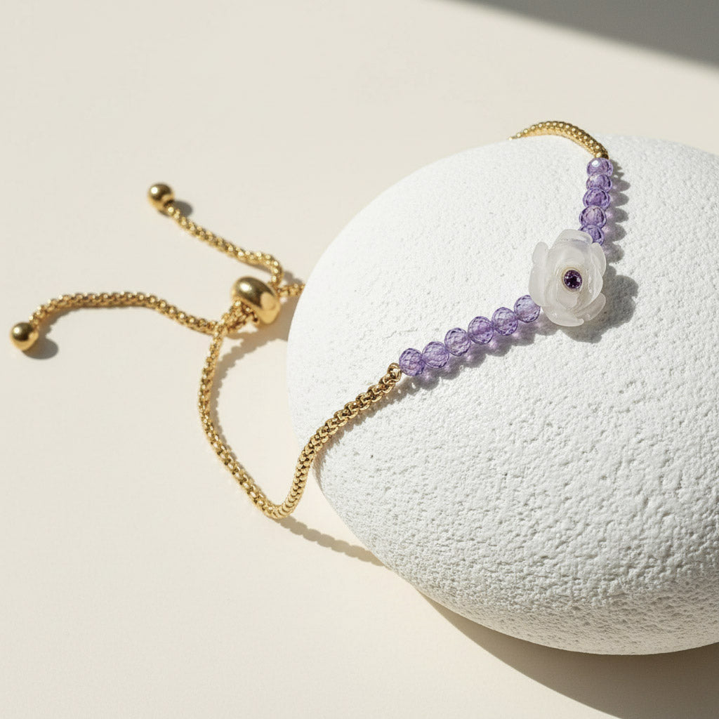 Gold adjustable bracelet with purple beads and white carved flower centrepiece featuring a small amethyst gem