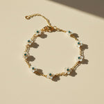 Gold bracelet with white floral charms on a beige background