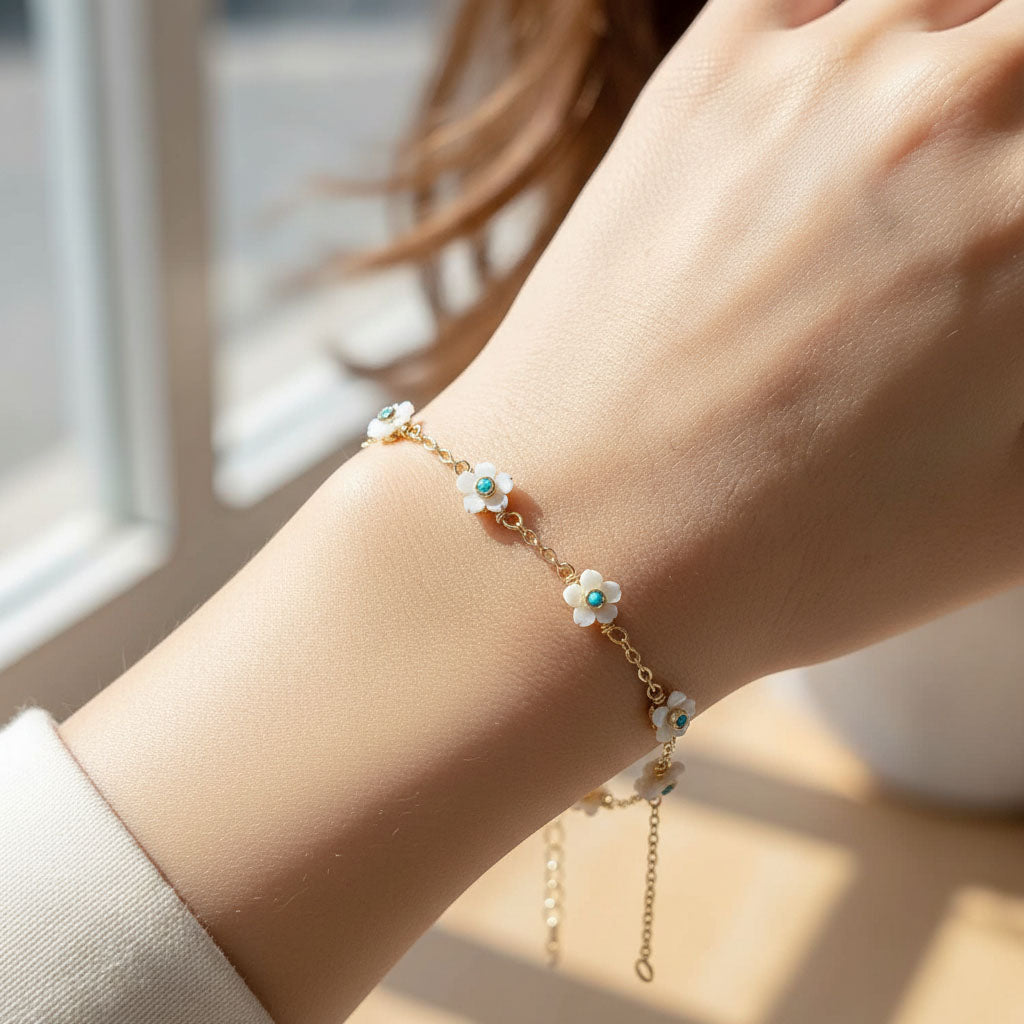 Gold bracelet with floral charms on a wrist, soft focus background