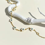 Gold chain necklace with floral pendants on a white branch