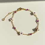 Gold bracelet with floral charms on a light beige background