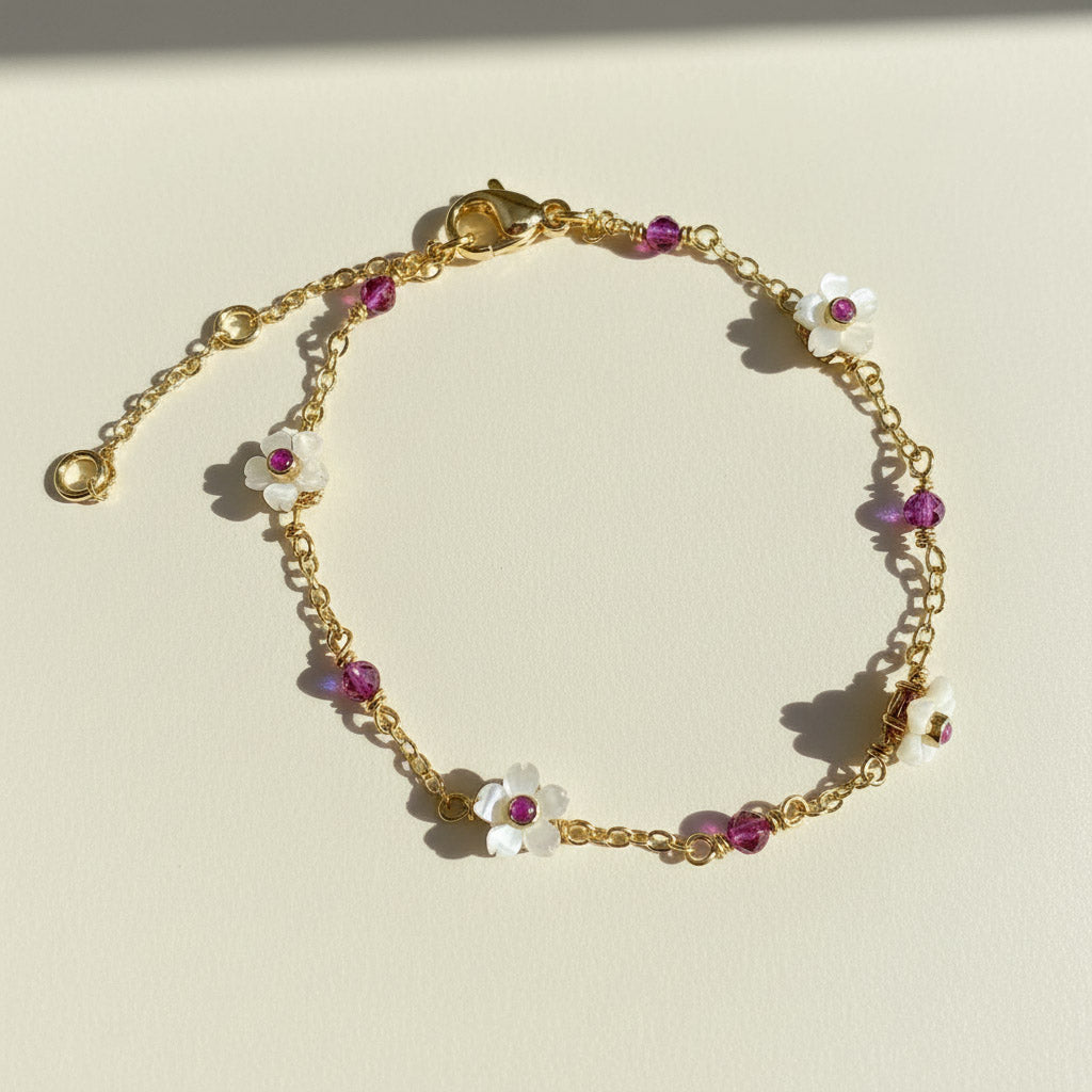 Gold bracelet with floral charms on a light beige background