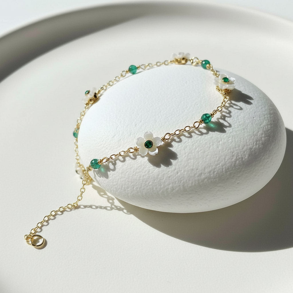 Gold bracelet with green beads on a white stand