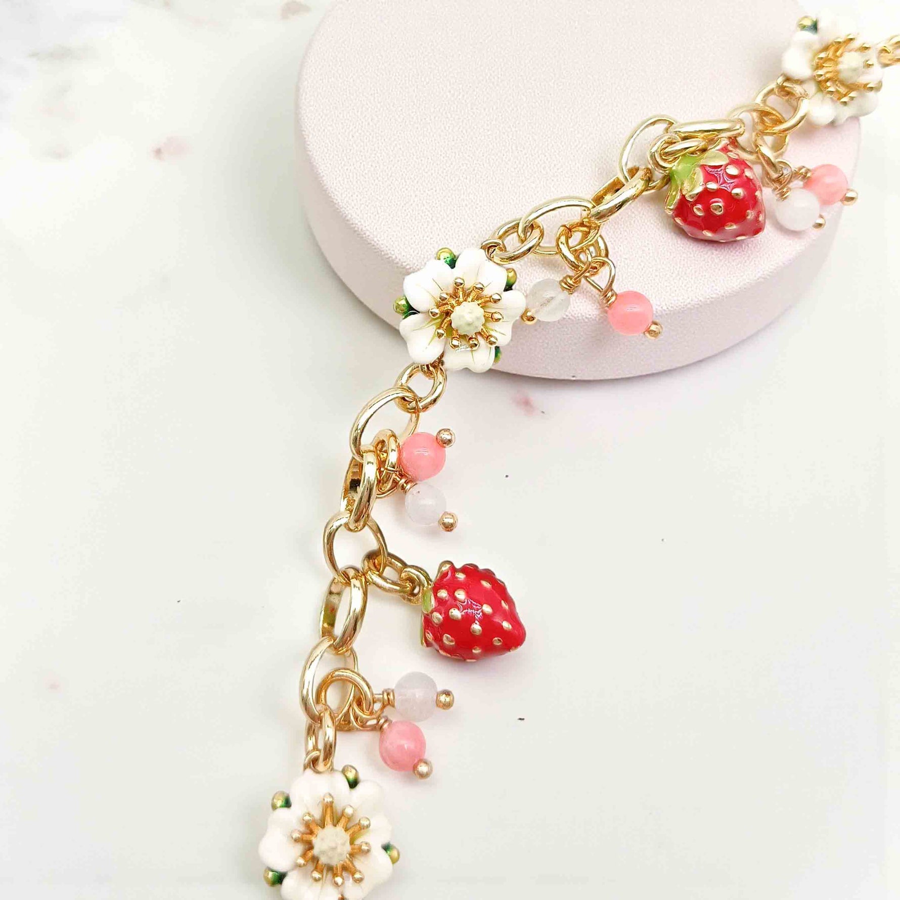 Bracelet with strawberry and flower charms on a white background