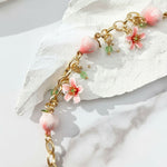 Bracelet with pink floral and spherical charms on a white stone background