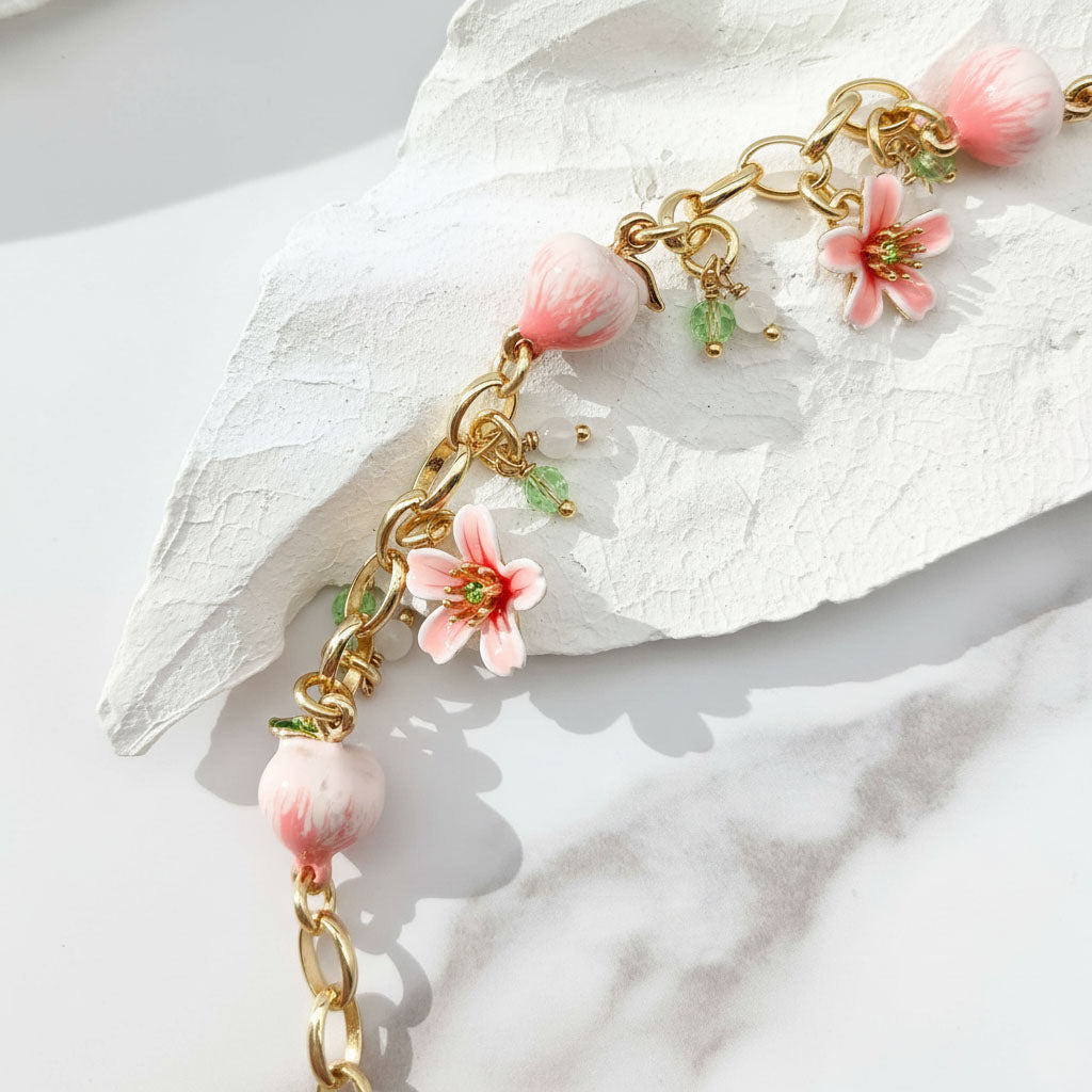 Bracelet with pink floral and spherical charms on a white stone background