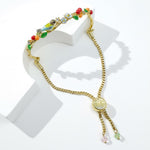 Gold bracelet with colorful charms on a white background