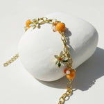 Gold bracelet with orange beads on a white stone