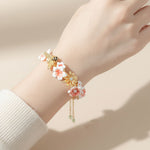 Delicate floral bracelet on a wrist against a neutral background
