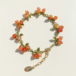 Bracelet with orange beads and gold chain on a light background