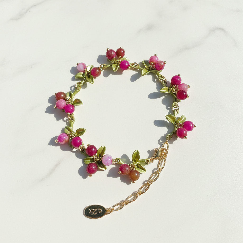 Bracelet with pink beads and gold chain on a white background