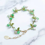Green beaded bracelet with gold chain on a marble surface