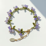 Bracelet with purple beads and gold chain on a light background