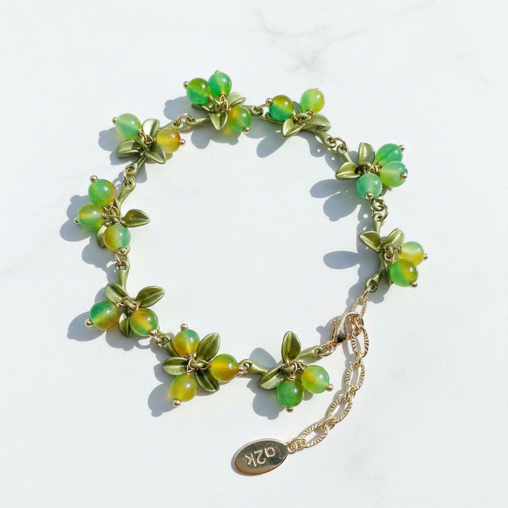 Green beaded bracelet with gold accents on a white background
