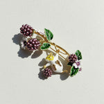 Decorative brooch with berries and a mouse on a light background