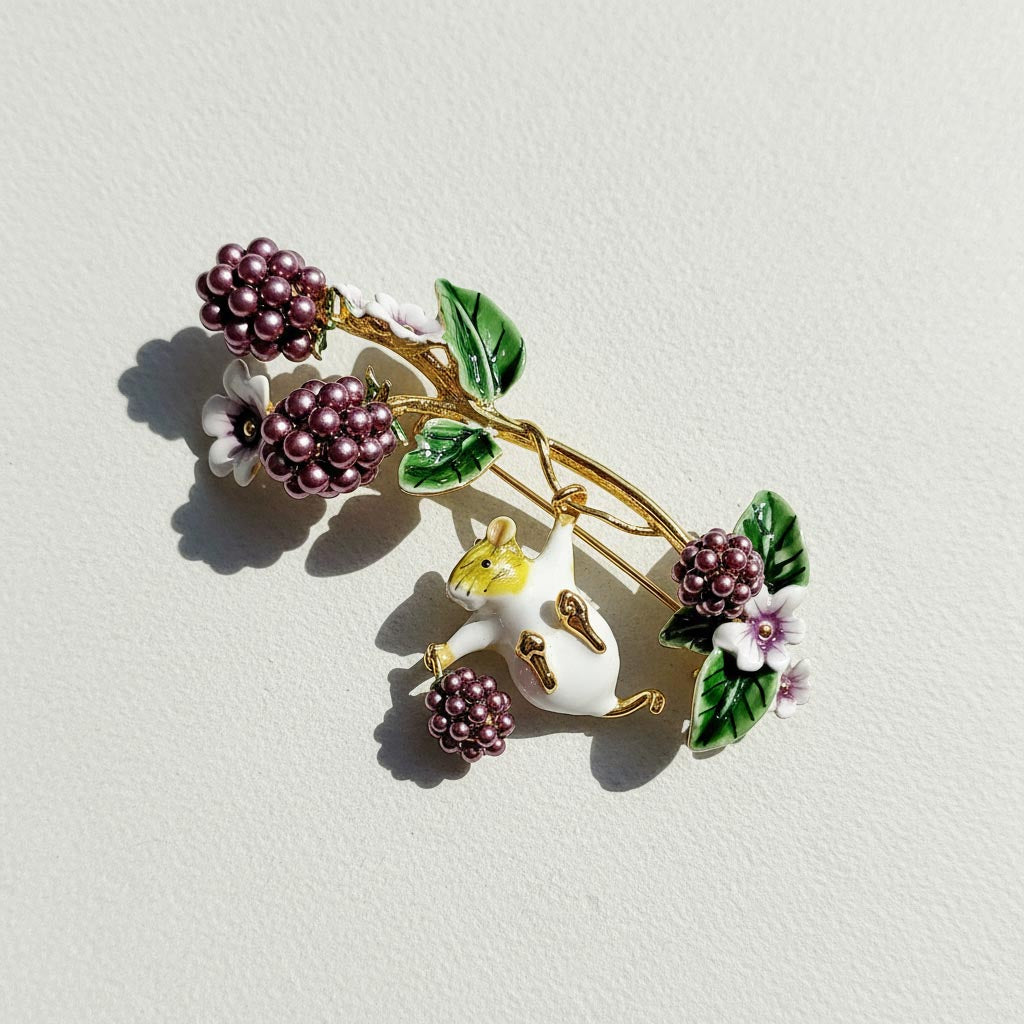 Decorative brooch with berries and a mouse on a light background