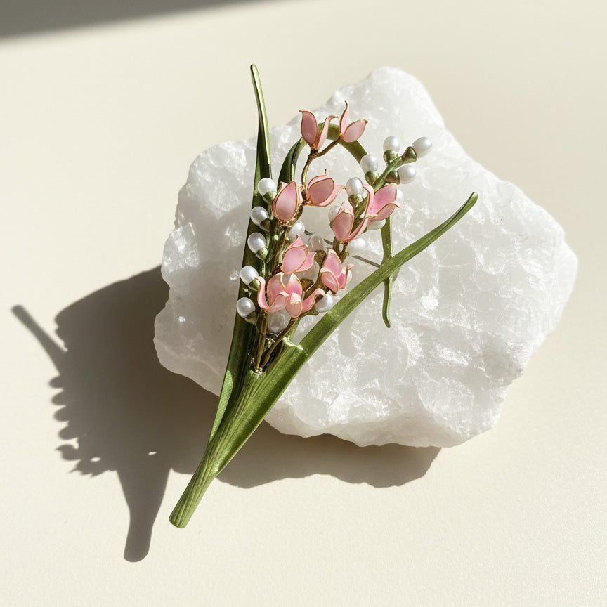 Lily of the valley floral brooch showing sculpted green stems and enamel detail