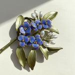 Close-up of blue floral brooch showing resin petals and leaf details