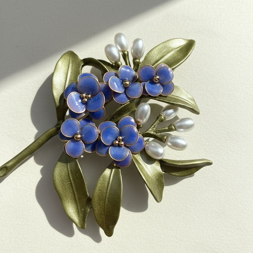 Close-up of blue floral brooch showing resin petals and leaf details