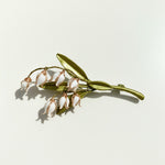 Side view of handcrafted floral brooch with resin buds and leaves