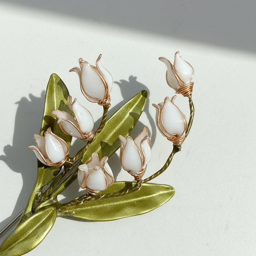Close-up of hand-painted lily of the valley resin flower brooch