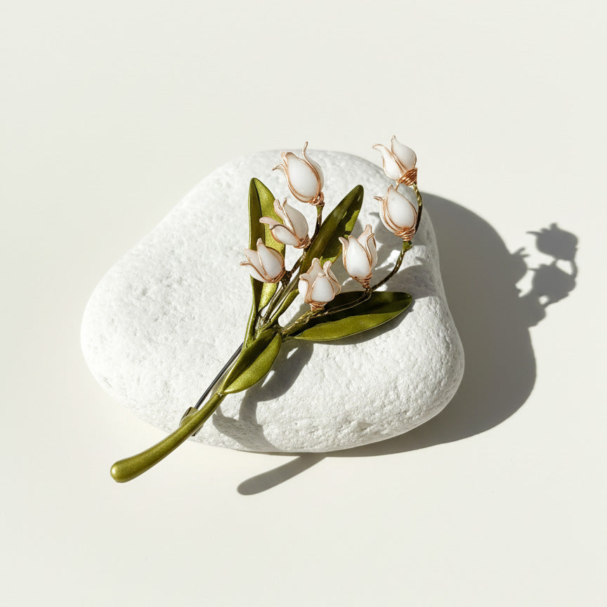 Handcrafted lily of the valley resin flower brooch on stone background