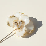 Close-up of hand-painted resin flower brooch with pearl and glass details