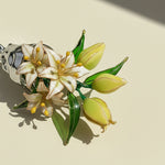 Floral brooch with white flowers and green leaves on a beige background