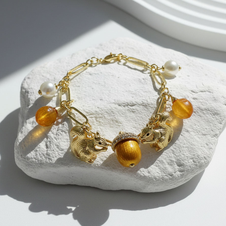 Bracelet with acorn and squirrel charms on a white stone surface