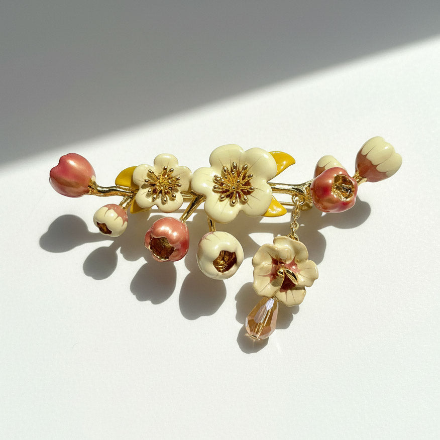 Floral brooch with pink, white, and gold flowers on a white background