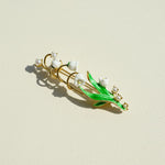 Jewelry brooch with green leaves and white pearls on a beige background