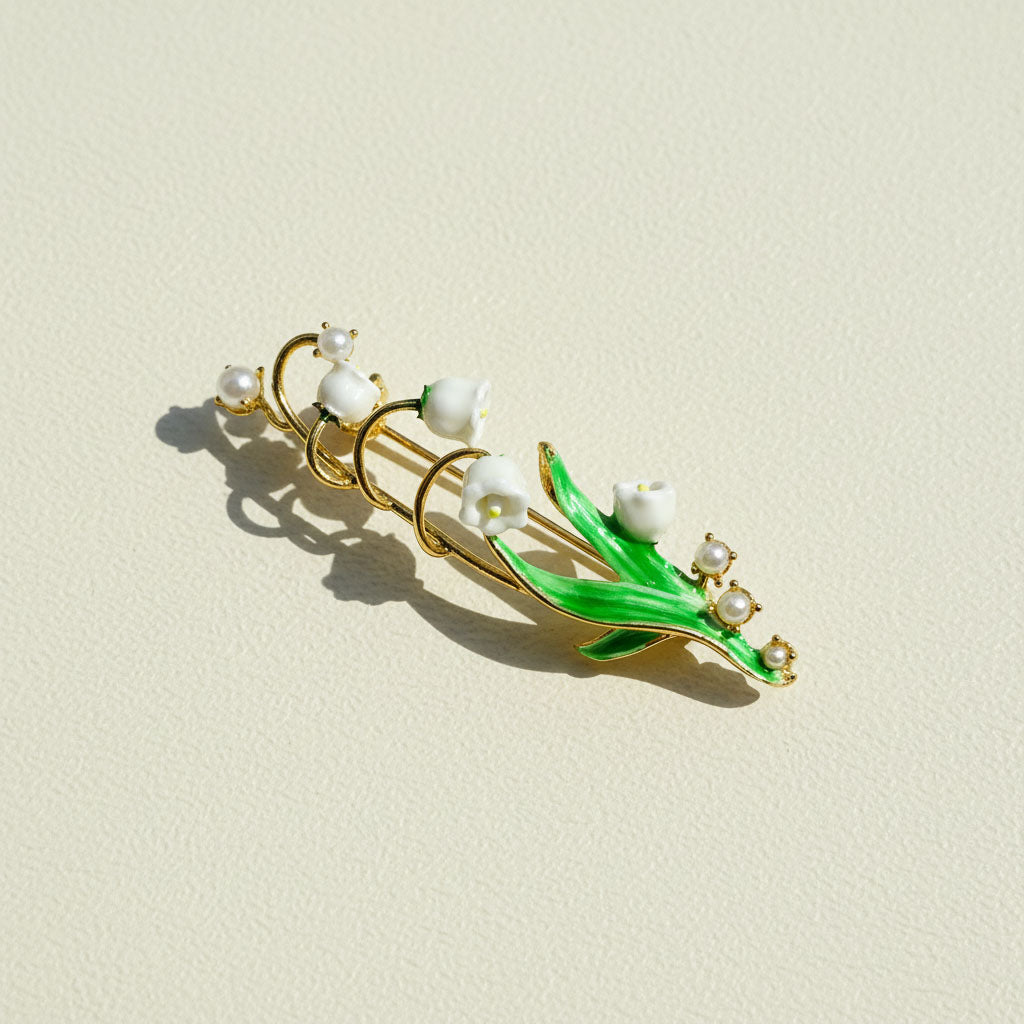 Jewelry brooch with green leaves and white pearls on a beige background